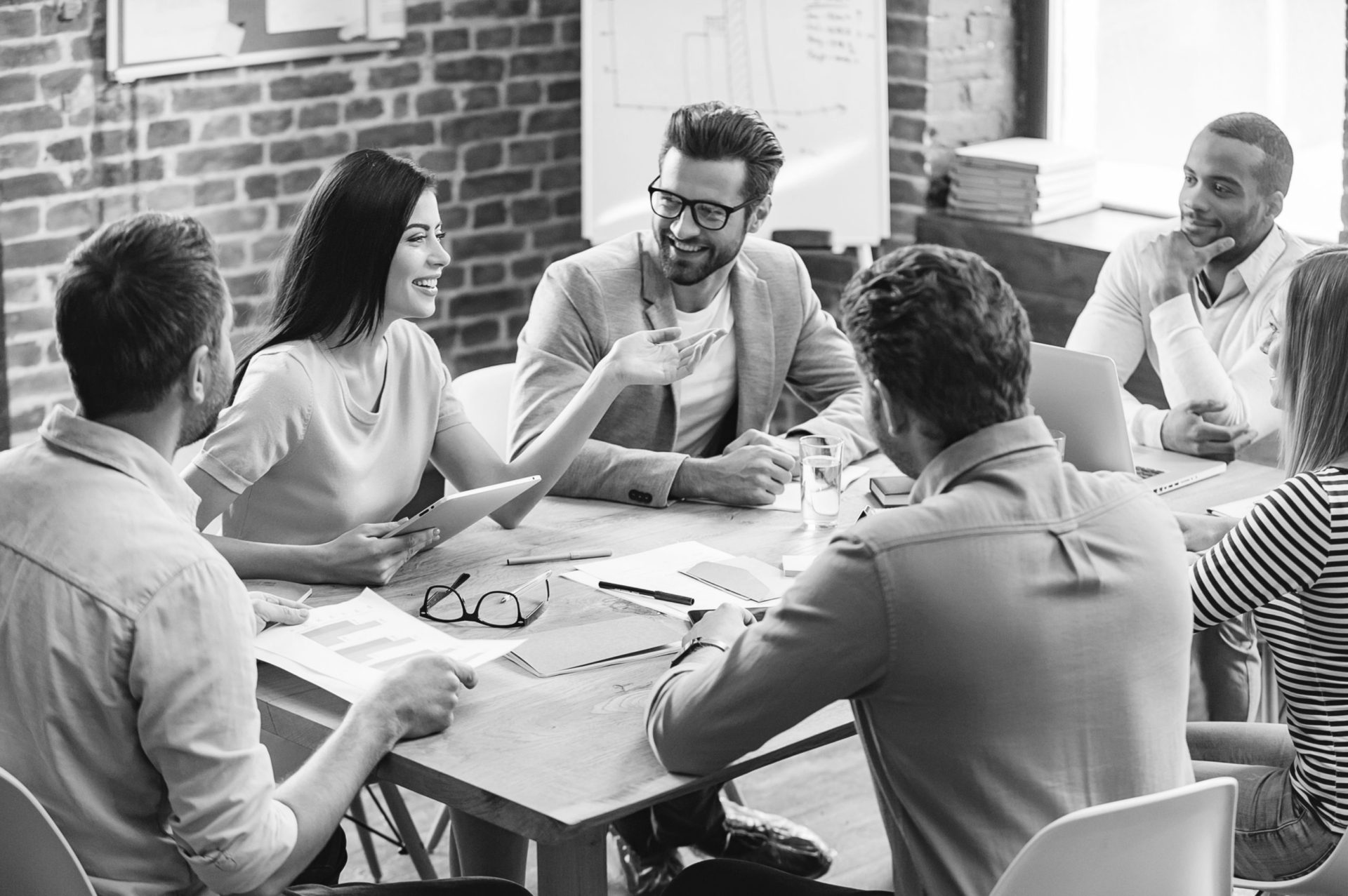 Making great decisions. Young beautiful woman gesturing and discussing something with smile while her coworkers listening to her sitting at the office table