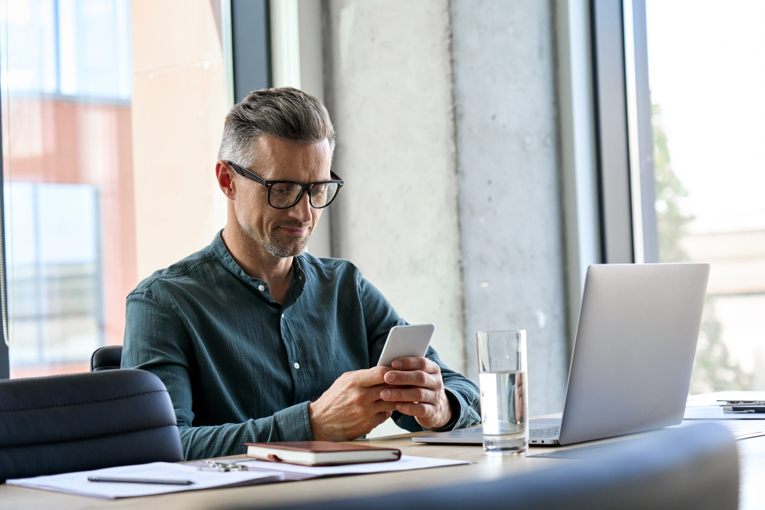 Smiling,Mature,Businessman,Holding,Smartphone,Sitting,In,Office.,Middle,Aged